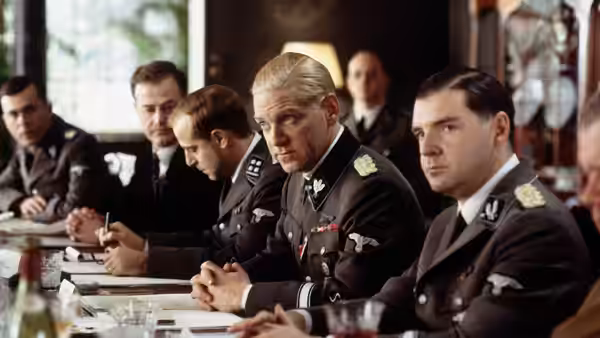 Reinhard Heydrich (Kenneth Branagh) sits with uniformed officials around a conference table