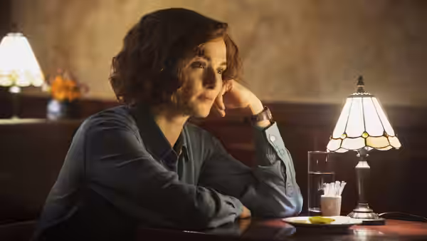 Deborah Lipstadt (Rachel Weisz) rests her head on one hand at a café table