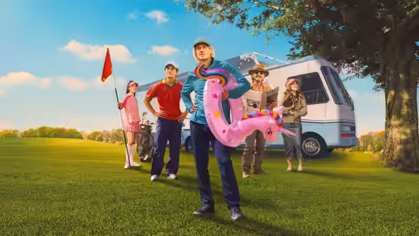 Pryce Cahill (Owen Wilson) holds a pink inflatable golf-course prop beside a camper van and group