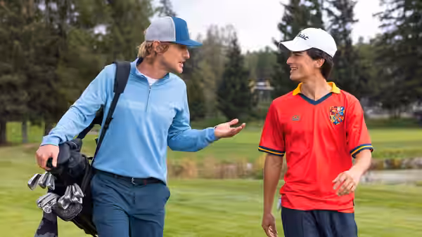 Pryce Cahill (Owen Wilson) chats with a young golfer carrying a golf bag