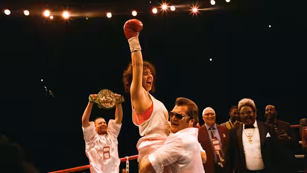 Christy Martin (Sydney Sweeney) raises a gloved fist in the boxing ring as officials watch