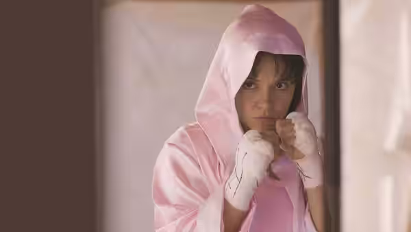 Christy Martin (Sydney Sweeney) raises her wrapped fists beneath a pink boxing hood