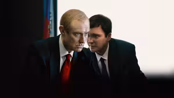 Vladimir Putin (Jude Law) listens as a man leans close to whisper