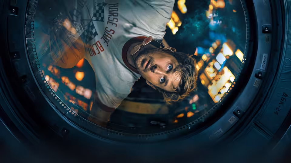 Ryan Gosling as Ryland Grace looking through a circular spacecraft hatch