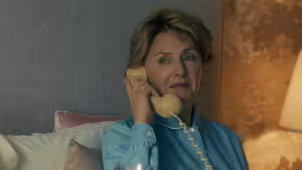 Nancy Reagan (Hope Davis) holds a yellow telephone while seated on a sofa
