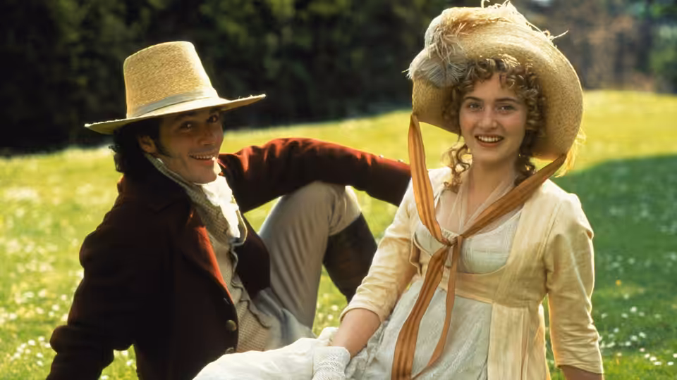 John Willoughby (Greg Wise) reclining beside Marianne Dashwood (Kate Winslet) on a grassy slope