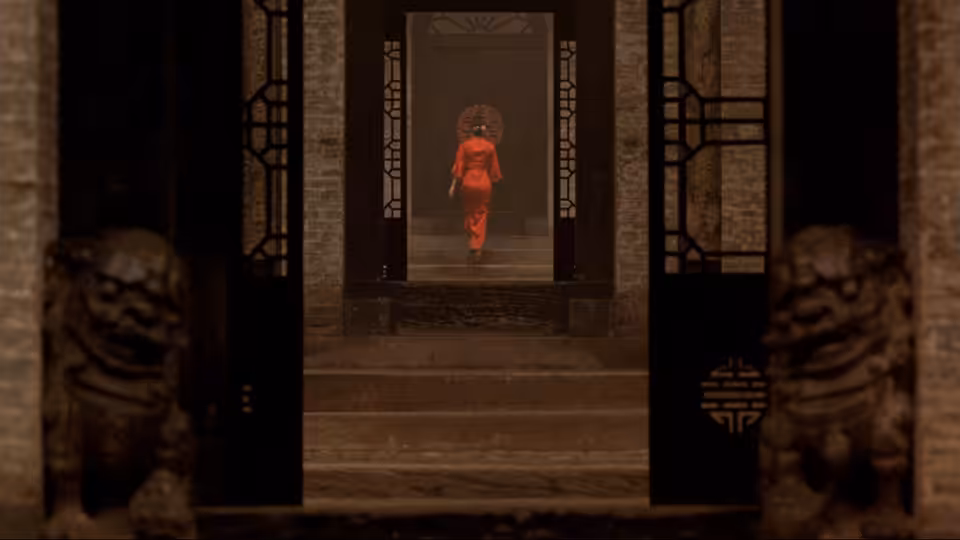 a woman in red walking through a traditional courtyard doorway