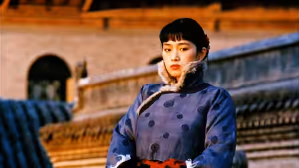 Songlian (Gong Li) in a blue coat before a stone wall