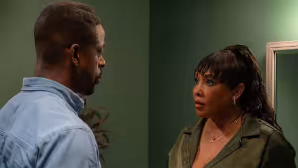 A man and a woman face each other in a dim green room