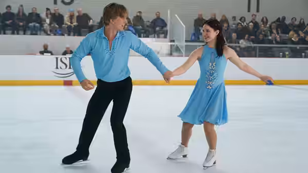 A pair of figure skaters hold hands on the ice rink