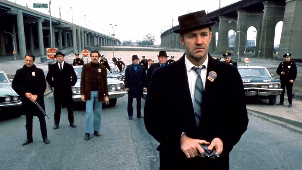 Popeye Doyle (Gene Hackman) leading armed detectives under a concrete overpass