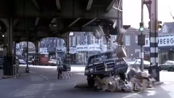 A car flipping and exploding under an elevated railway in a city street