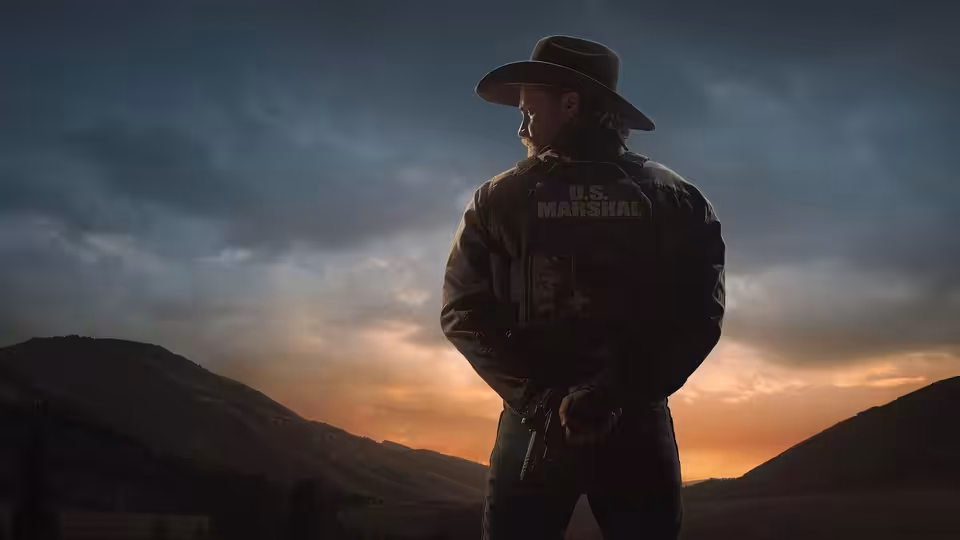 A marshal stands silhouetted against the sunset with his hands clasped