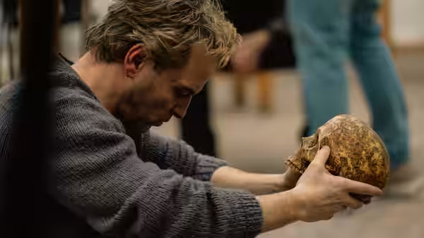 A man bends over a rough stone object, holding it carefully in both hands