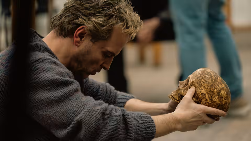 A man bends over a rough stone object, holding it carefully in both hands