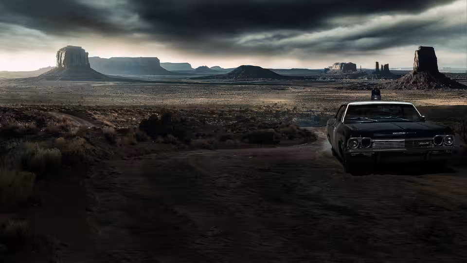 A dark car sits on a dirt road beneath storm clouds in the desert