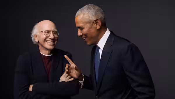 Larry David and Barack Obama smile as Obama gestures toward David's hand