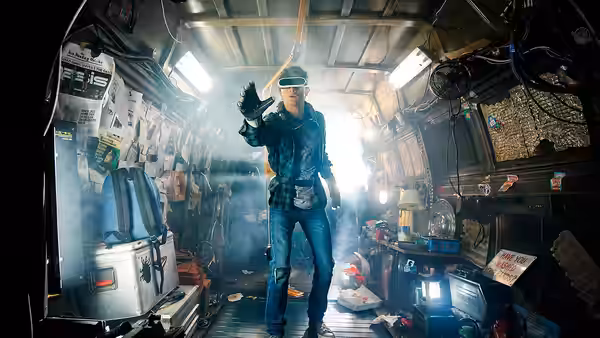 A visor-wearing man stands inside a cramped room filled with equipment