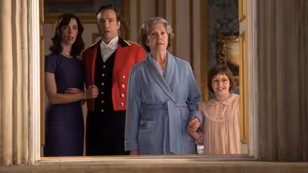 The Queen (Penelope Wilton) and Sophie (Ruby Barnhill) stand with palace staff in a doorway
