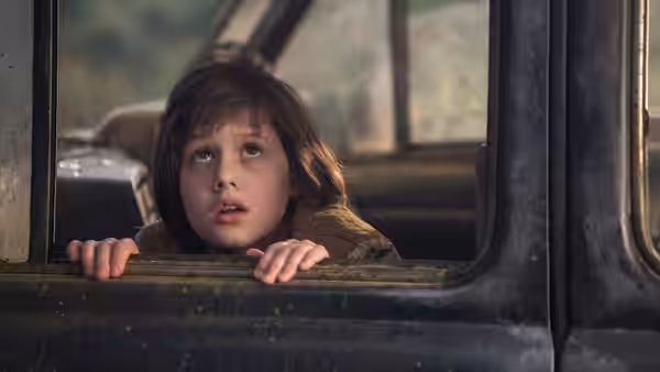 Sophie (Ruby Barnhill) peers through a vehicle window, gripping its lower edge