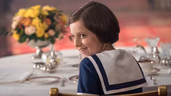 Sophie (Ruby Barnhill) looks back from her chair at a dining table