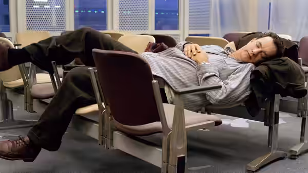 Viktor Navorski (Tom Hanks) stretches across a row of airport seats