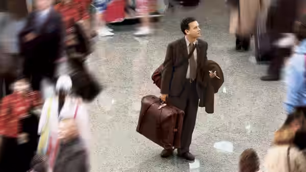 Viktor Navorski (Tom Hanks) stands in the airport terminal with two suitcases