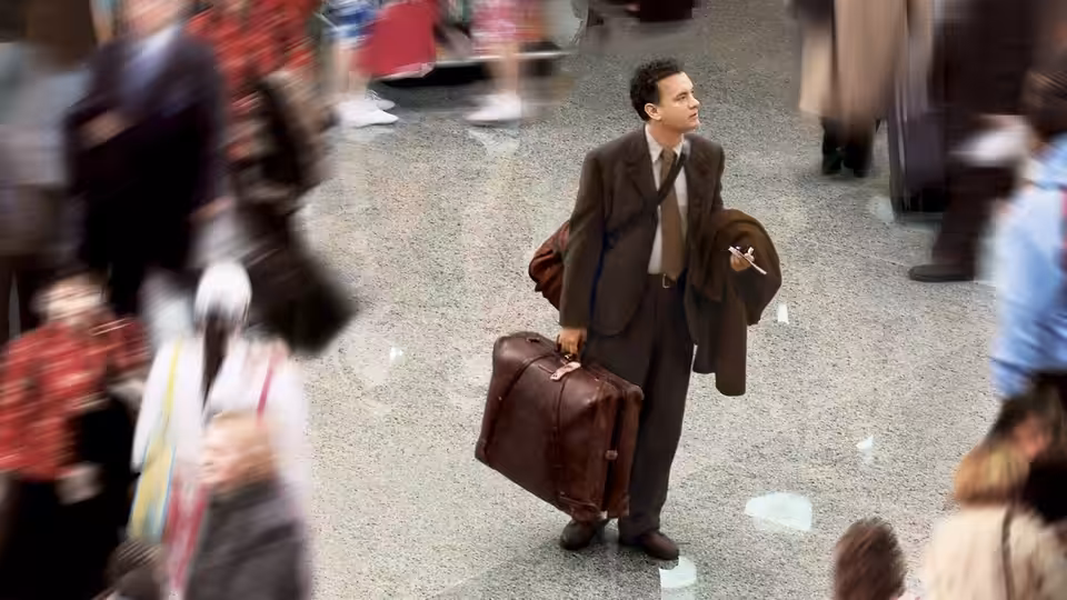 Viktor Navorski (Tom Hanks) stands in the airport terminal with two suitcases