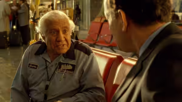 Gupta Rajan (Kumar Pallana) talks with Viktor Navorski (Tom Hanks) beside terminal seating