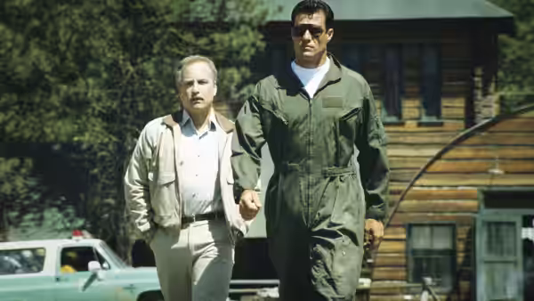 Pete Sandich (Richard Dreyfuss) walks beside Ted Baker (Brad Johnson) outside a wooden building