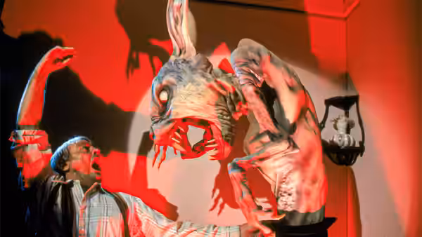A man watches a distorted figure suspended upside down in a room