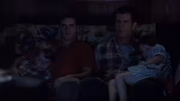 Graham and Merrill sit with Morgan and Bo in darkness, the children wearing foil hats