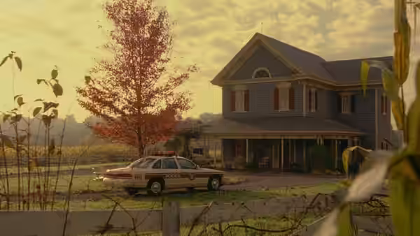 A police cruiser is parked outside the Hess farmhouse beside the cornfield