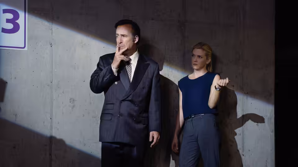 Jimmy McGill (Bob Odenkirk) and Kim Wexler (Rhea Seehorn) stand by a concrete wall