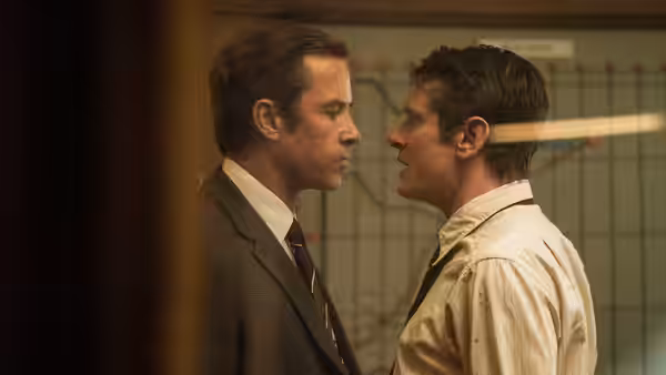 Two men face each other at close range in an office