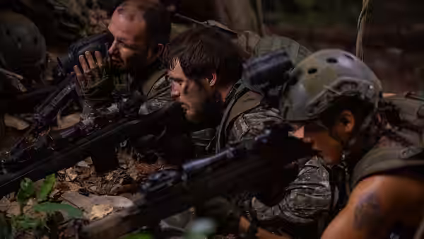 Three armed soldiers crouch among leaves, aiming rifles through the forest