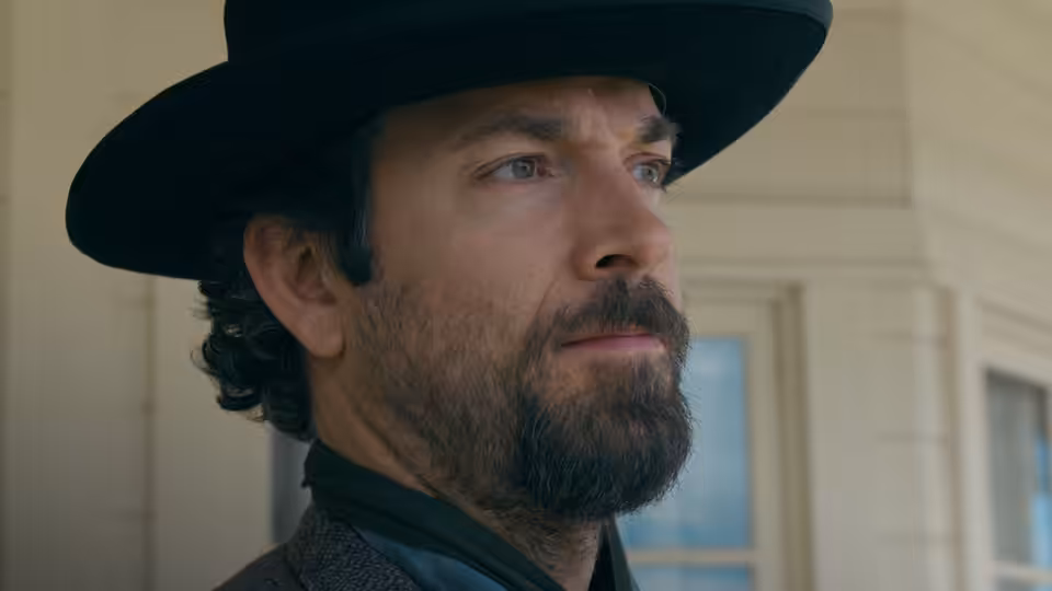 Quirt Evans (Zachary Levi) in a black hat, looking off-camera indoors