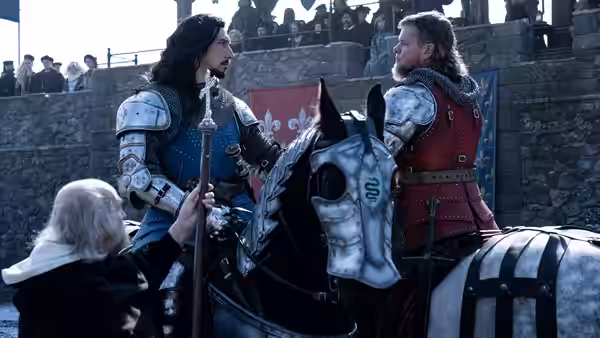 Two armored men face each other in a courtyard as an attendant adjusts one man's armor