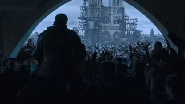 A mounted figure addresses a crowd beneath an arch, with wooden scaffolding beyond
