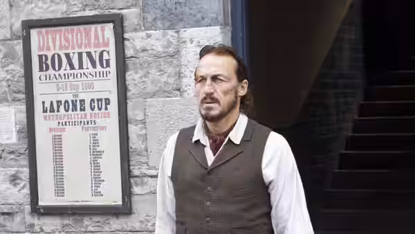 Bennet Drake (Jerome Flynn) stands beside a divisional boxing championship poster