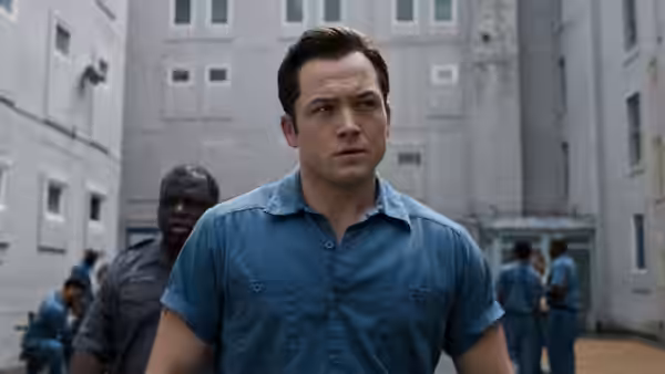 James Keene (Taron Egerton) walks through a prison yard as inmates gather behind him