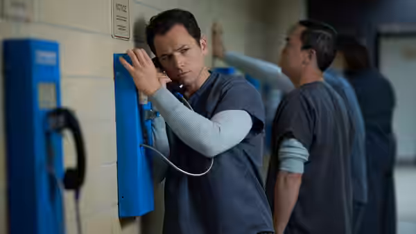James Keene (Taron Egerton) uses a wall phone in a prison corridor