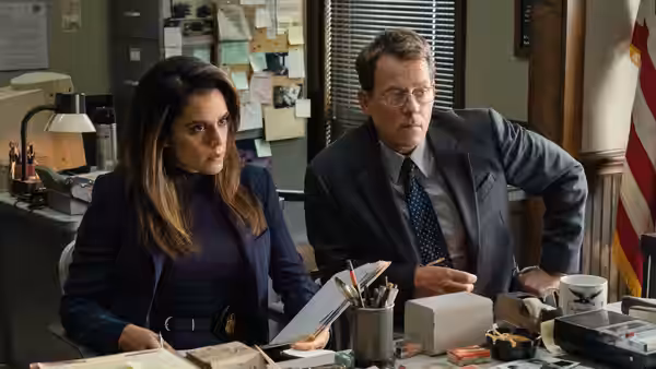 Lauren McCauley (Sepideh Moafi) and Brian Miller (Greg Kinnear) sit at a cluttered office desk