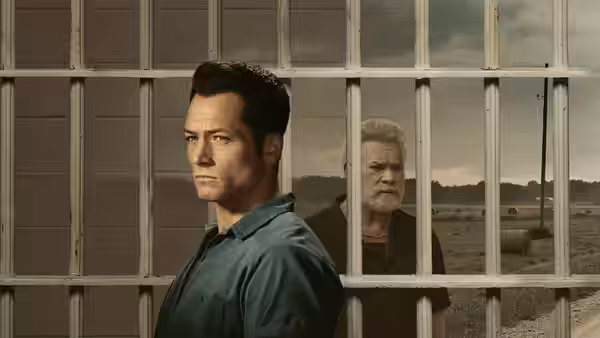 James Keene (Taron Egerton) stands by barred windows as an older man watches from behind