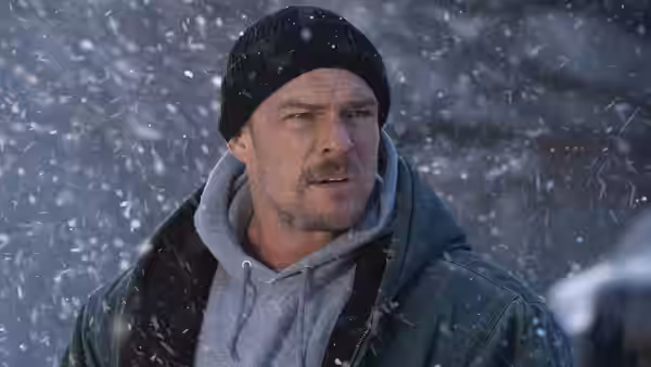 Ed Schmitt (Alan Ritchson) in a beanie and winter jacket as snow falls