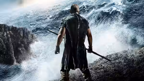 Noah (Russell Crowe) stands on a rocky shore facing a towering wave, staff in hand