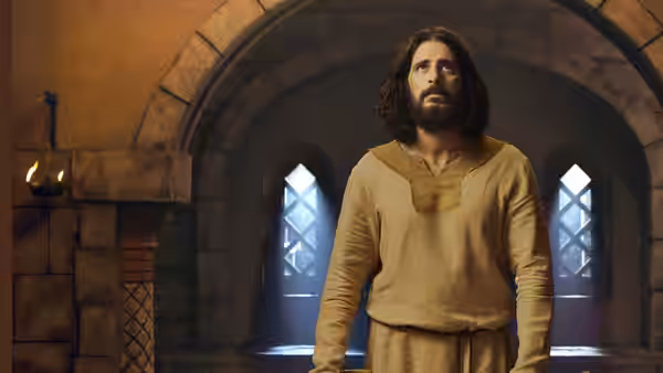 Jesus (Jonathan Roumie) stands beneath a stone arch between two windows
