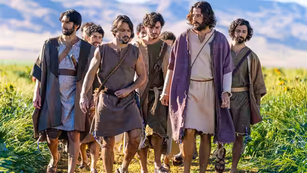 Jesus (Jonathan Roumie) and his followers walk through a grassy field