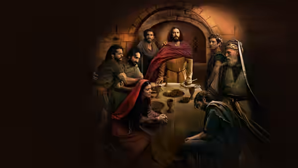 Jesus (Jonathan Roumie) shares a meal with his followers around a table