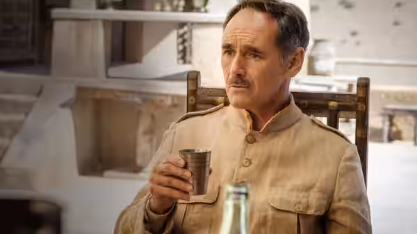 The Magistrate (Mark Rylance) holds a metal cup in his quarters